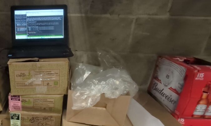 Clinton's laptop running Claude Code, sitting on some boxes at his Beer Store job.